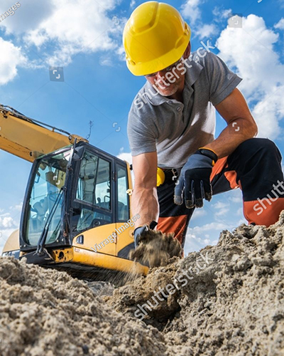 stock photo a construction worker is kneeling in the sand using his hands to dig while an excavator operates 2656204885